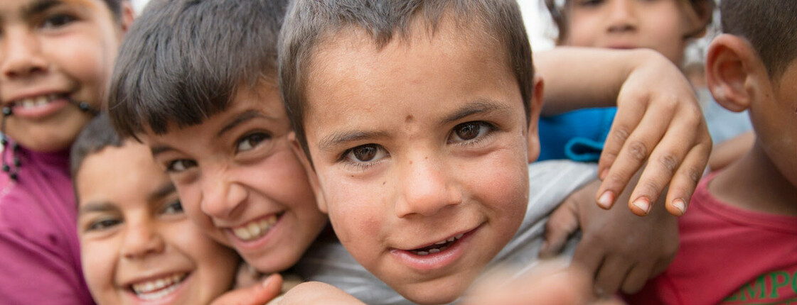 Gesichter von mehreren lachenden Kindern, die sich umarmen