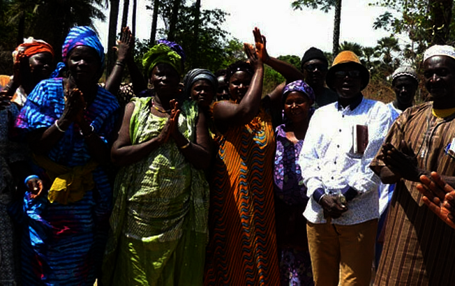 Gruppe von Menschen in der Region Ziguinchor, Senegal, die an einem Caritas-Projekt zur Errichtung von Brunnen und Dämmen teilnehmen und lächeln.